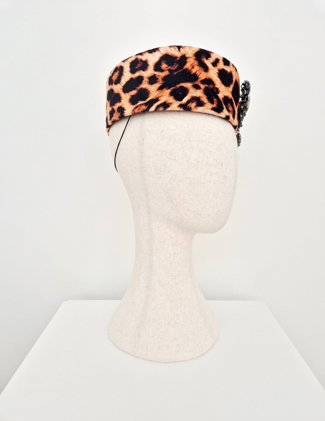 Leopard print headpiece on a mannequin head against a white background side view