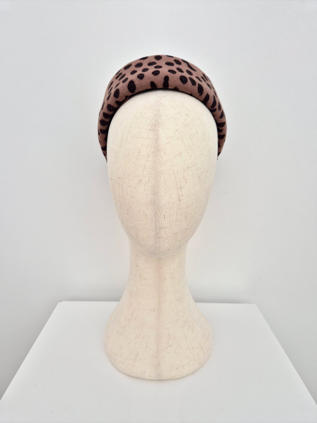 Leopard print pillbox headpiece on a mannequin head against a white background