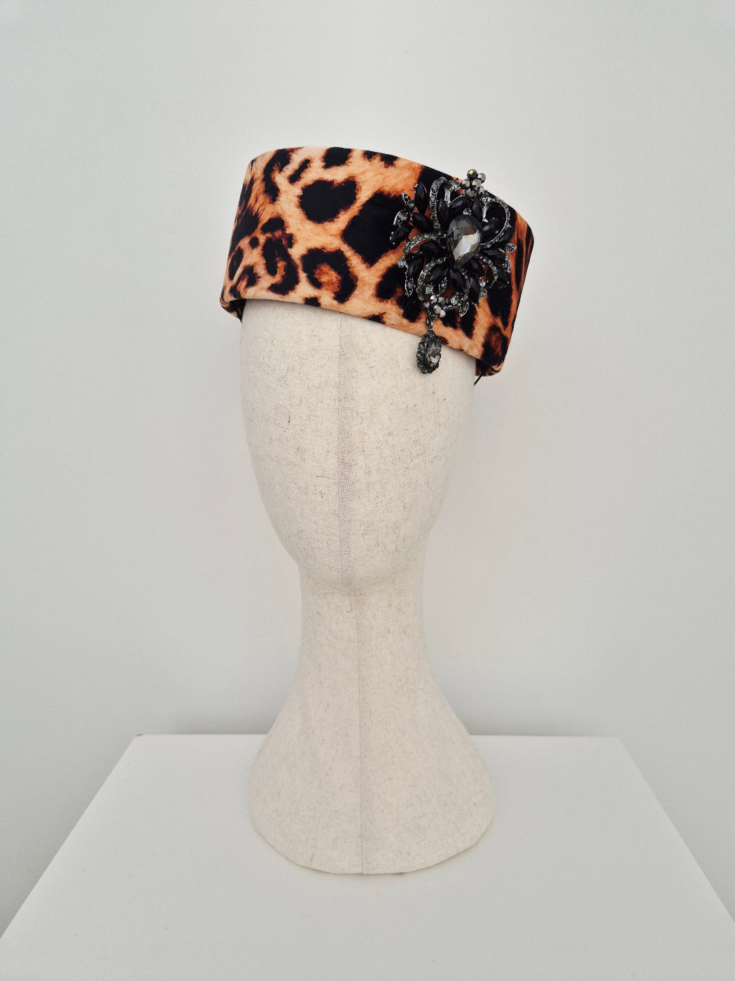 Leopard print headpiece pillbox on a mannequin head against a white background