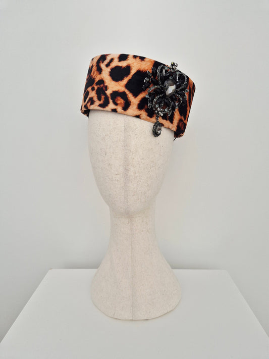 Leopard print headpiece pillbox on a mannequin head against a white background