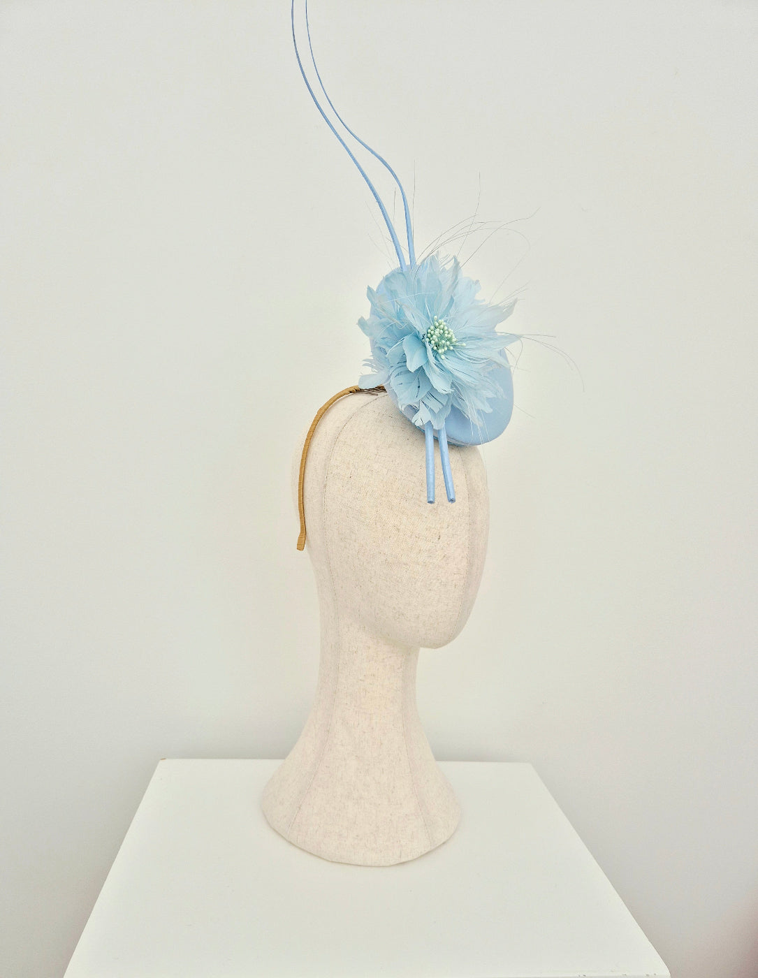 Light blue floral headpiece with flower on a mannequin head against a white background side view