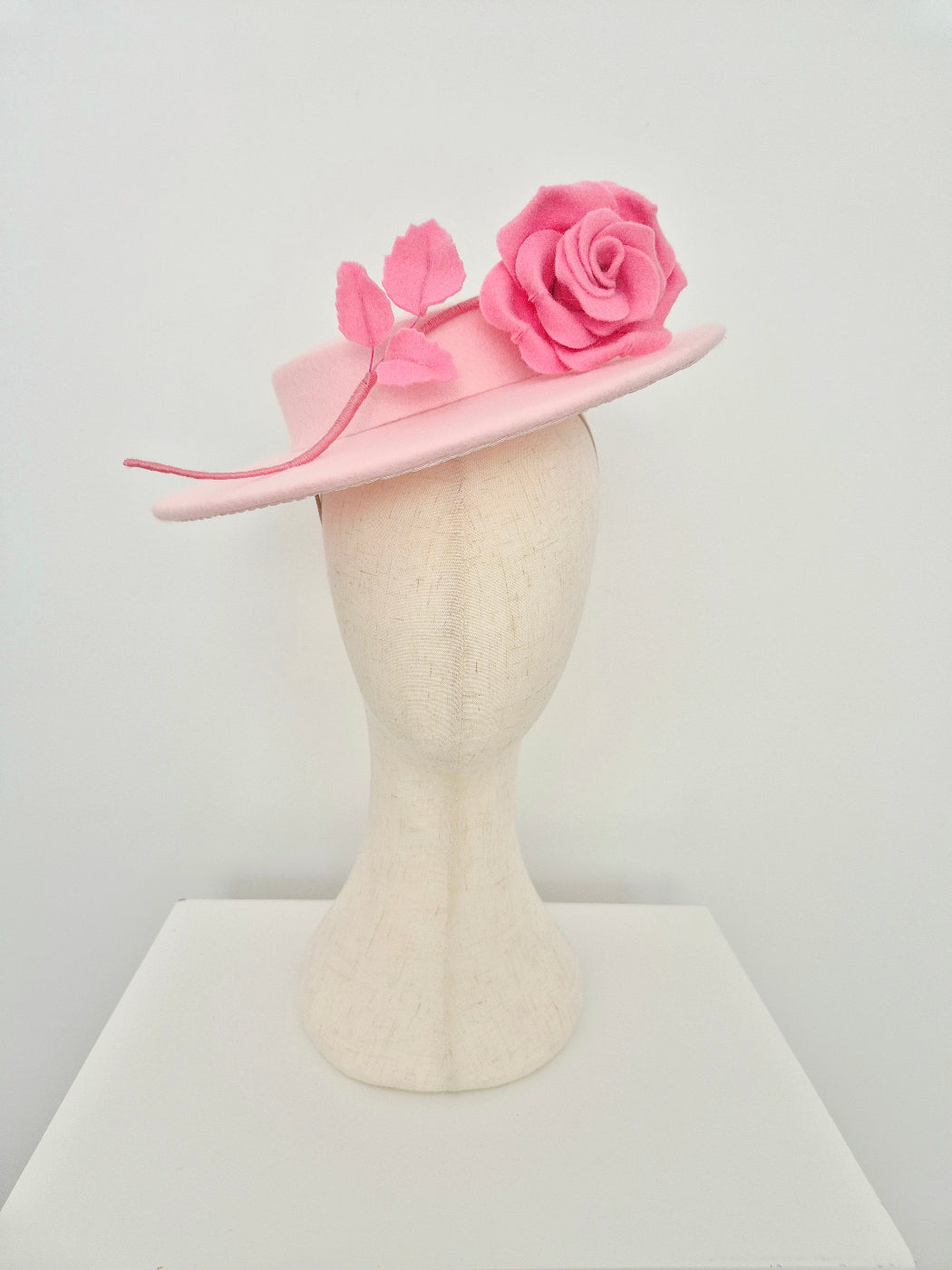 light Pink felt  hat with rose flower stem on a mannequin head against a white background