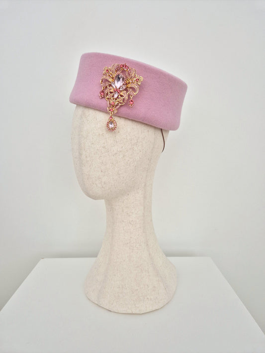 Pink hat with decorative brooch on a mannequin head against a white background side view