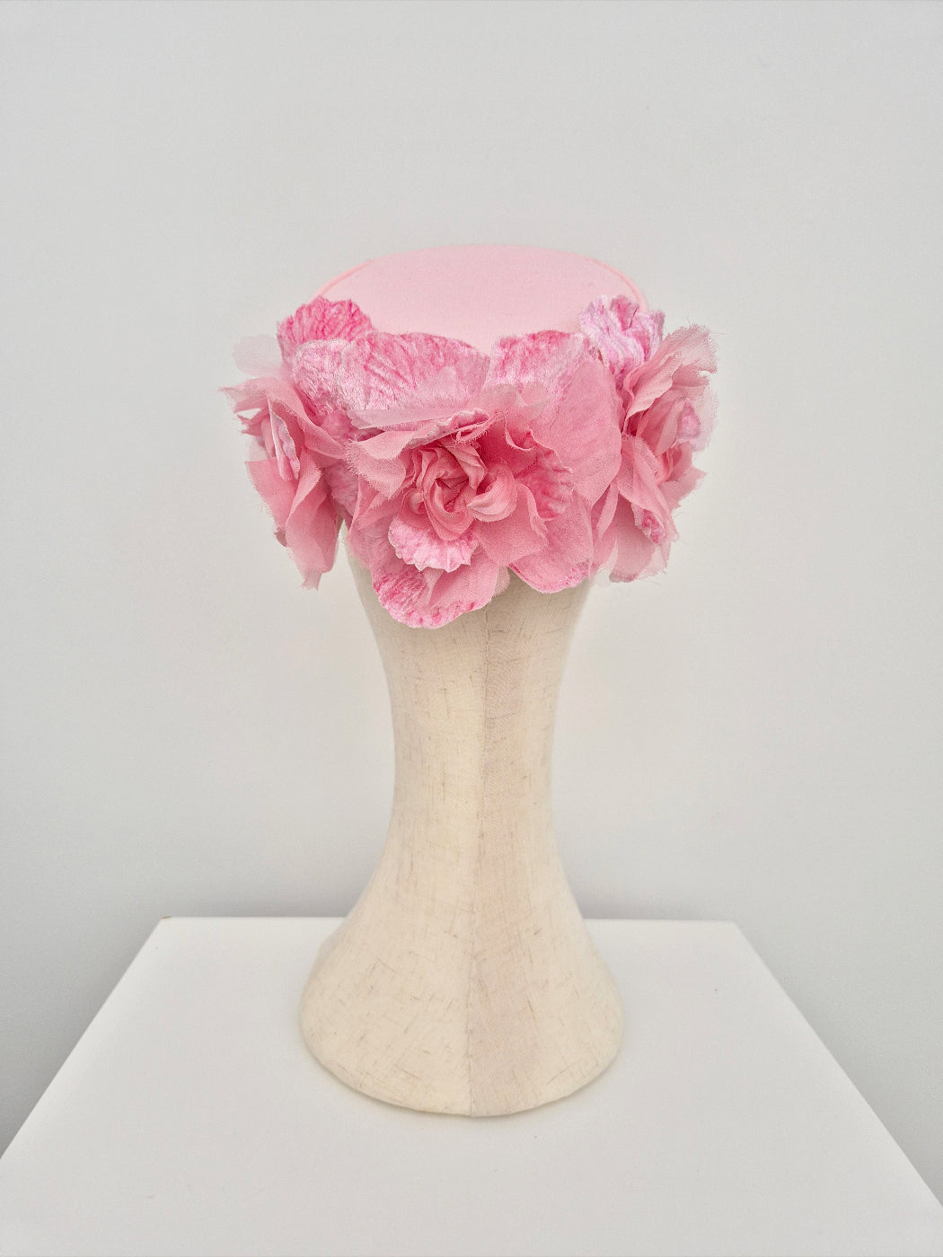 Pink floral pillbox headpiece on a mannequin head against a white background back view