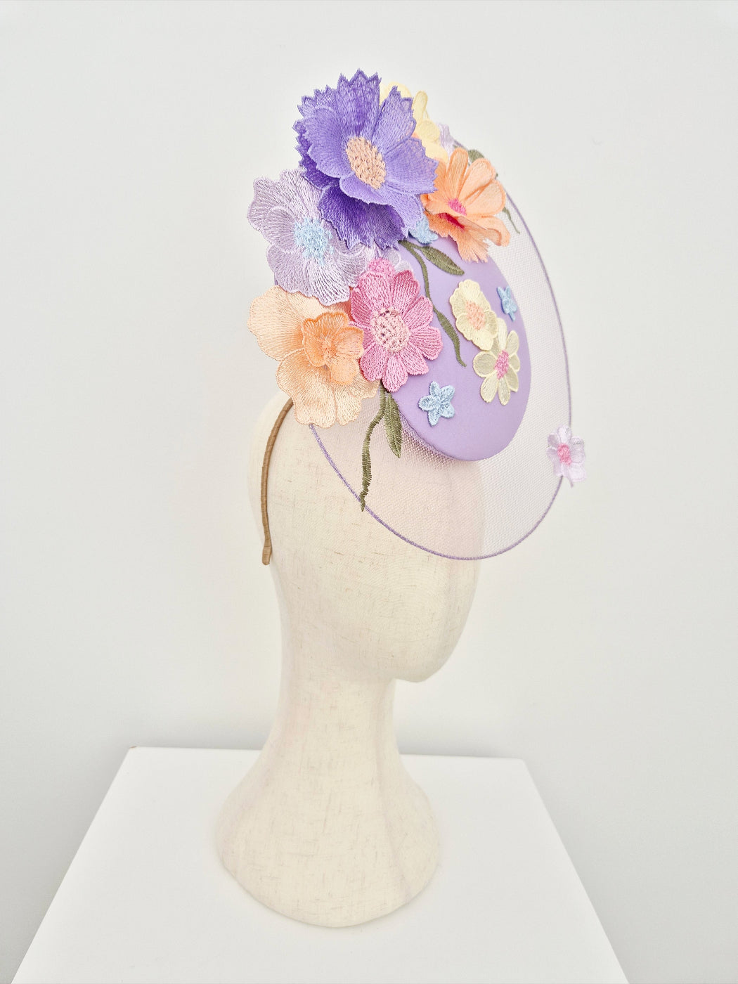 lilac and pastel floral headpiece on a mannequin head against a white background side view