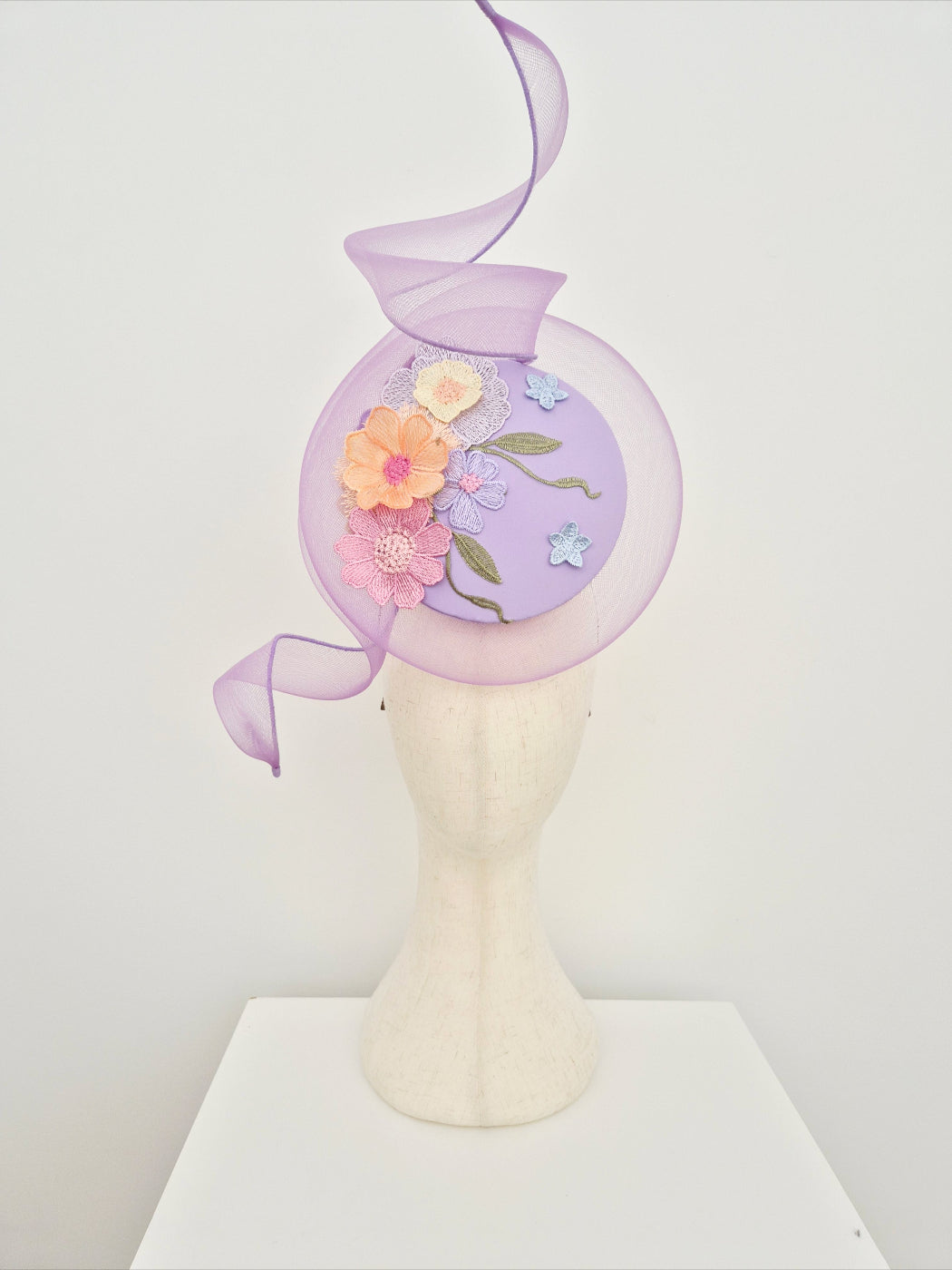 lilac-percher-headpiece-with-lace-detail on a manniquin head against a white wall