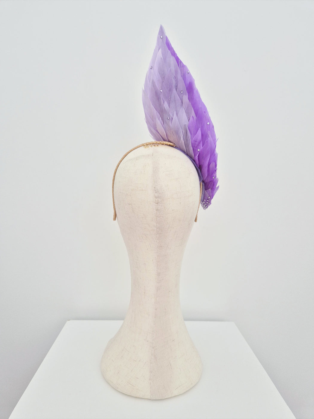 lilac ombre feather headpiece back view on a   mannequin head against a white background