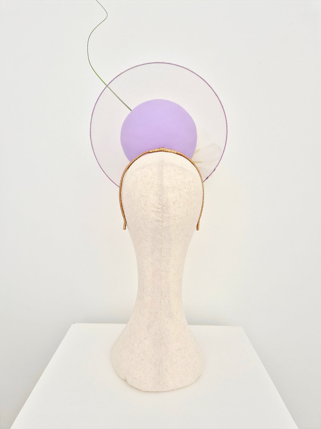 lilac percher headpiece with sheer disk on a manniquin head against a white wall back view