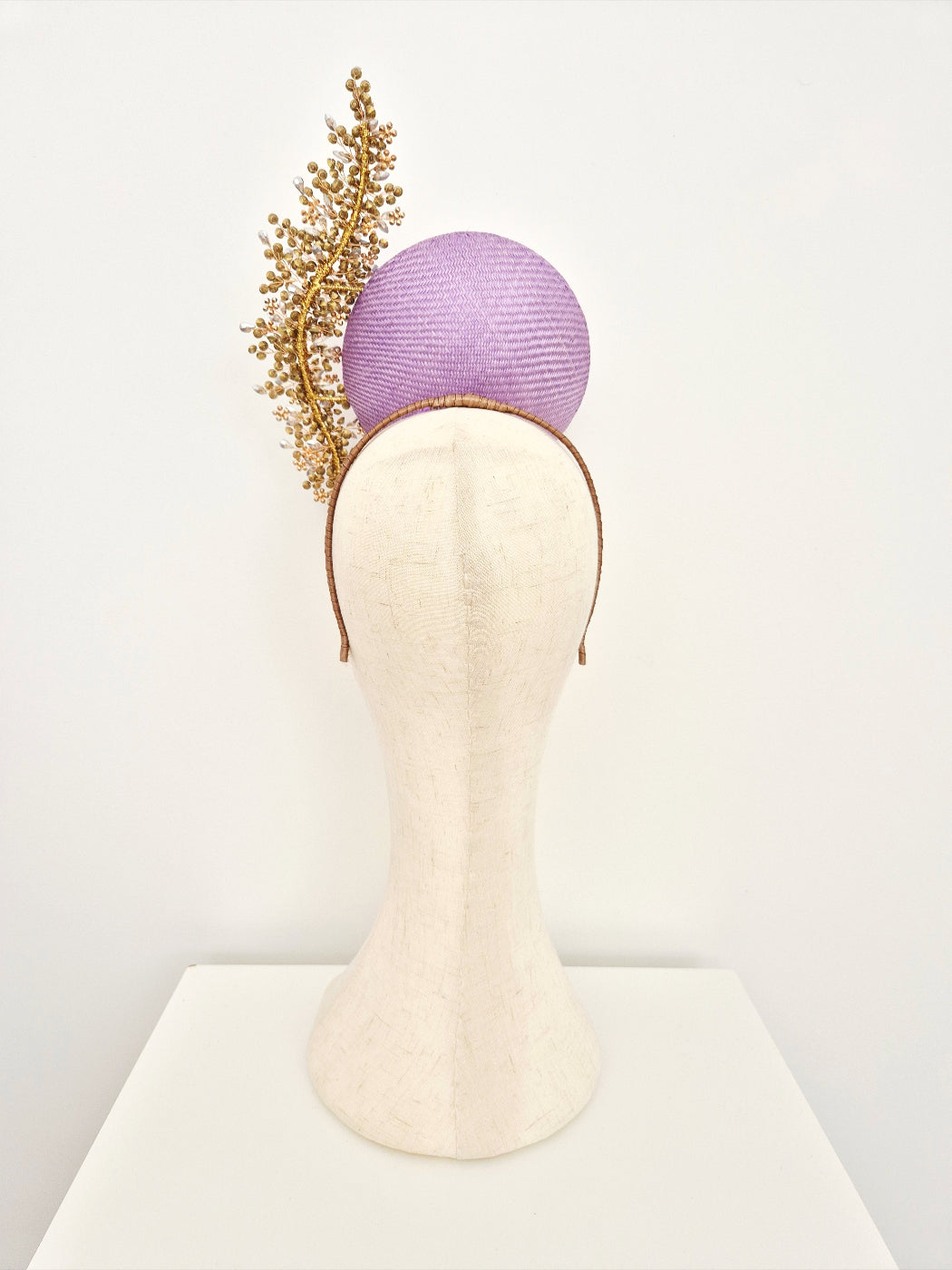 Purple headband with gold leaves on a mannequin head against a white background back view