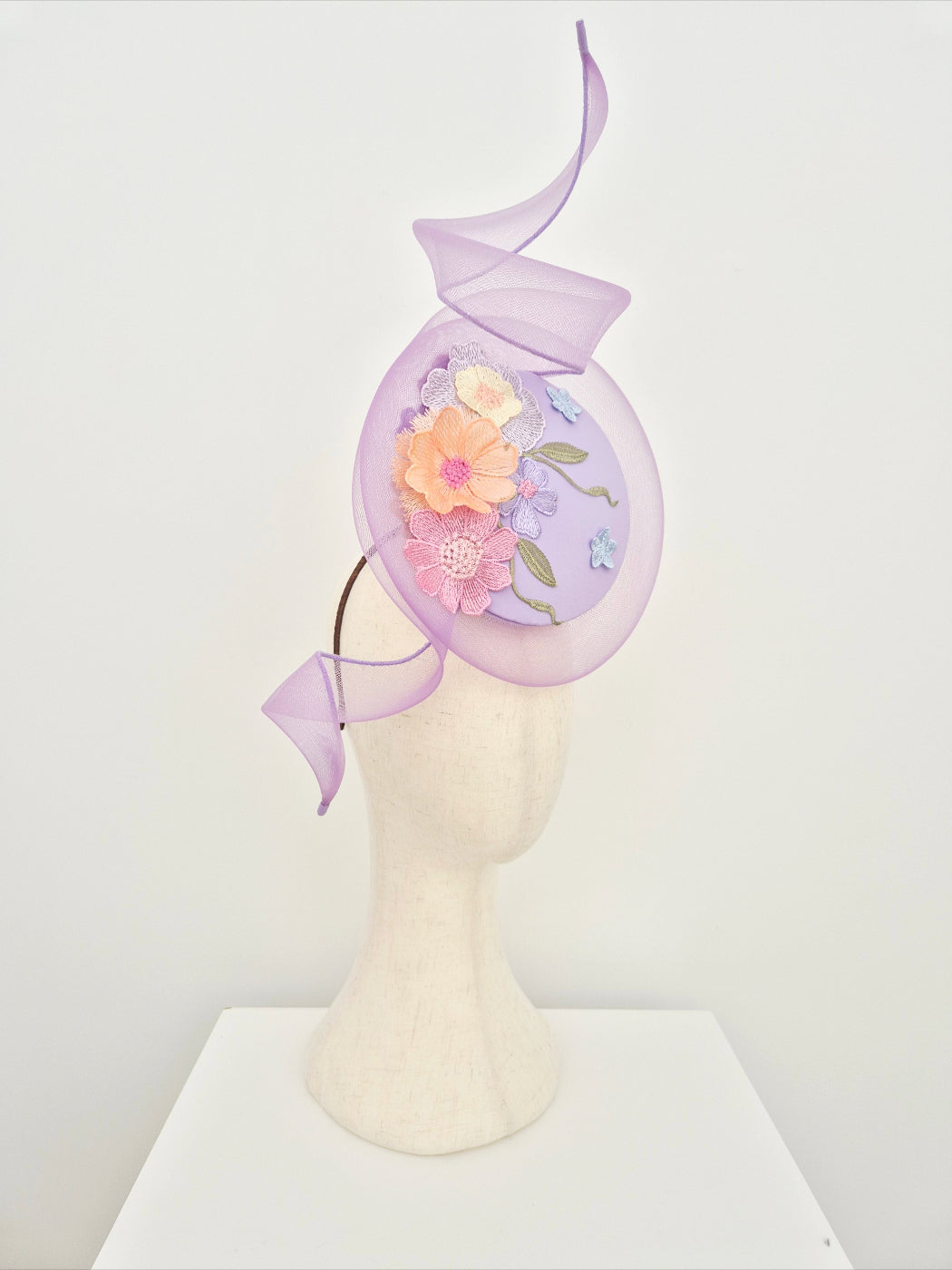 Decorative headpiece with flowers and swirl on a mannequin head against a white background