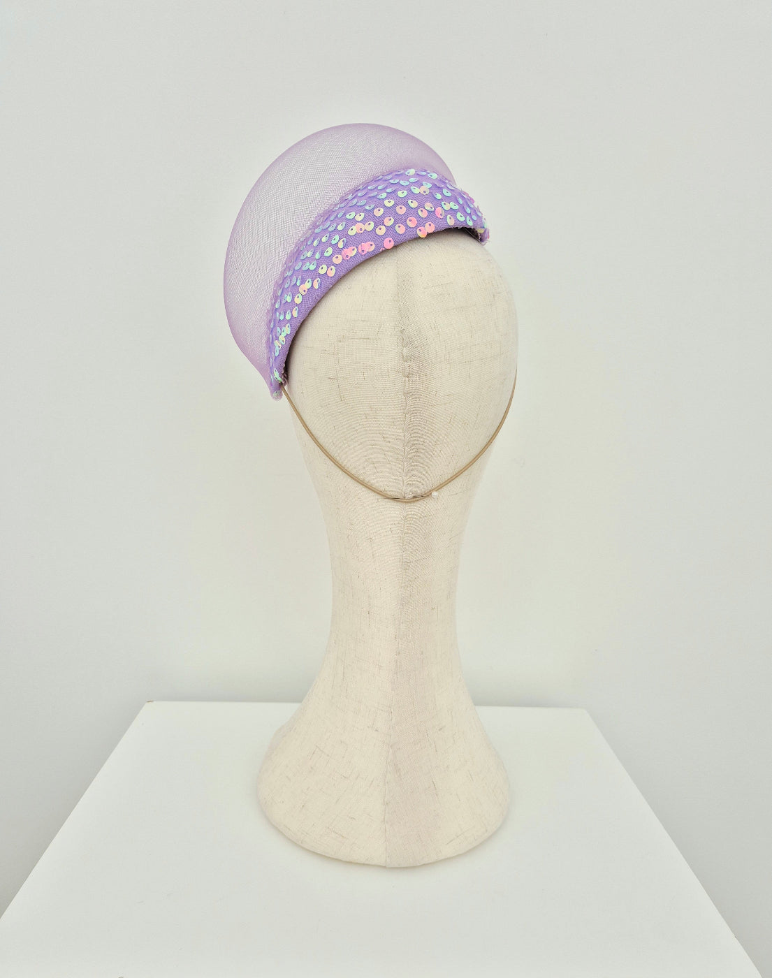 Lilac sequin headpiece on a mannequin head against a white background back view