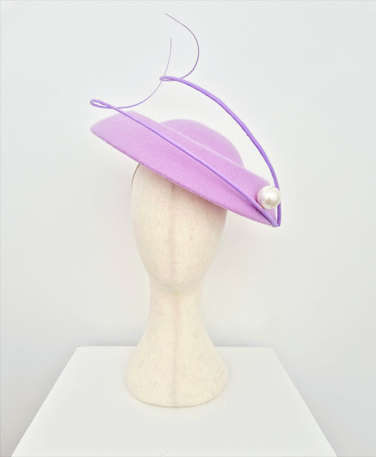 Lilac hat with a pearl on a mannequin head against a white background