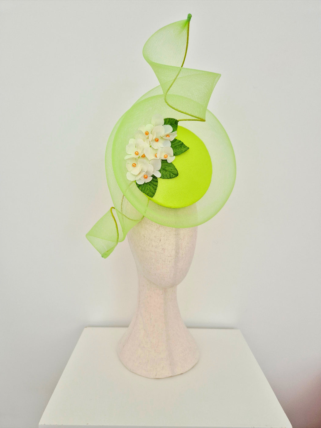 lime Green decorative percher headpiece with floral detail on a mannequin head against a white background side front view