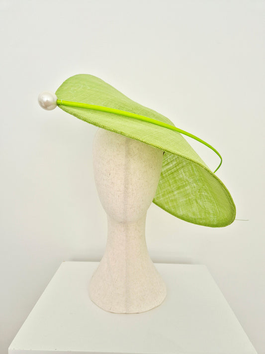 A light green fascinator hat with a matching green headband and a white pearl accent, displayed on a cream-colored mannequin head against a white background.option 2 position