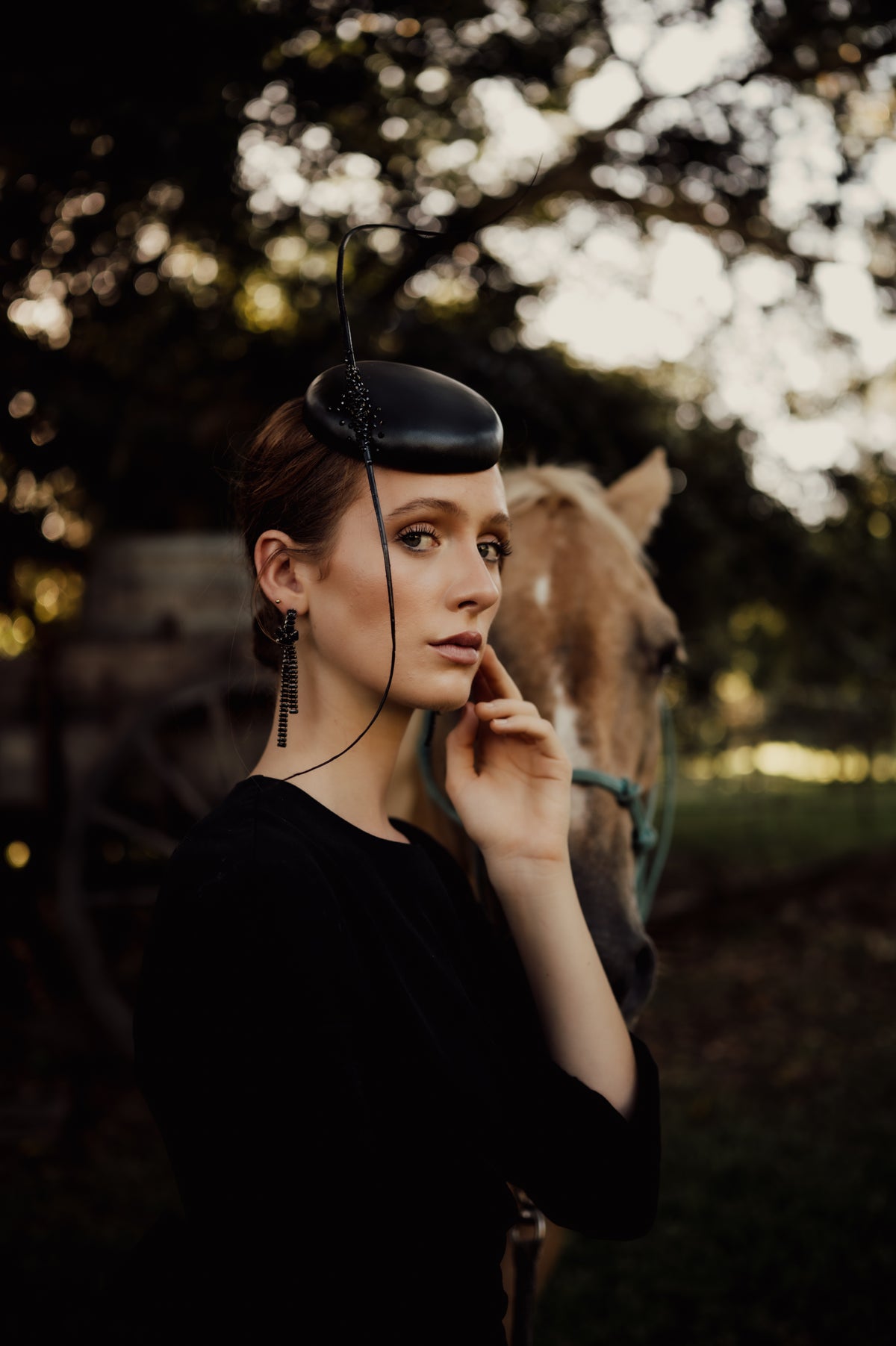 model wearing black headpiece with quills with a horse in the background