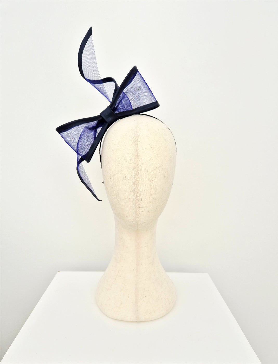 Navy blue bow headband on a mannequin head against a white background