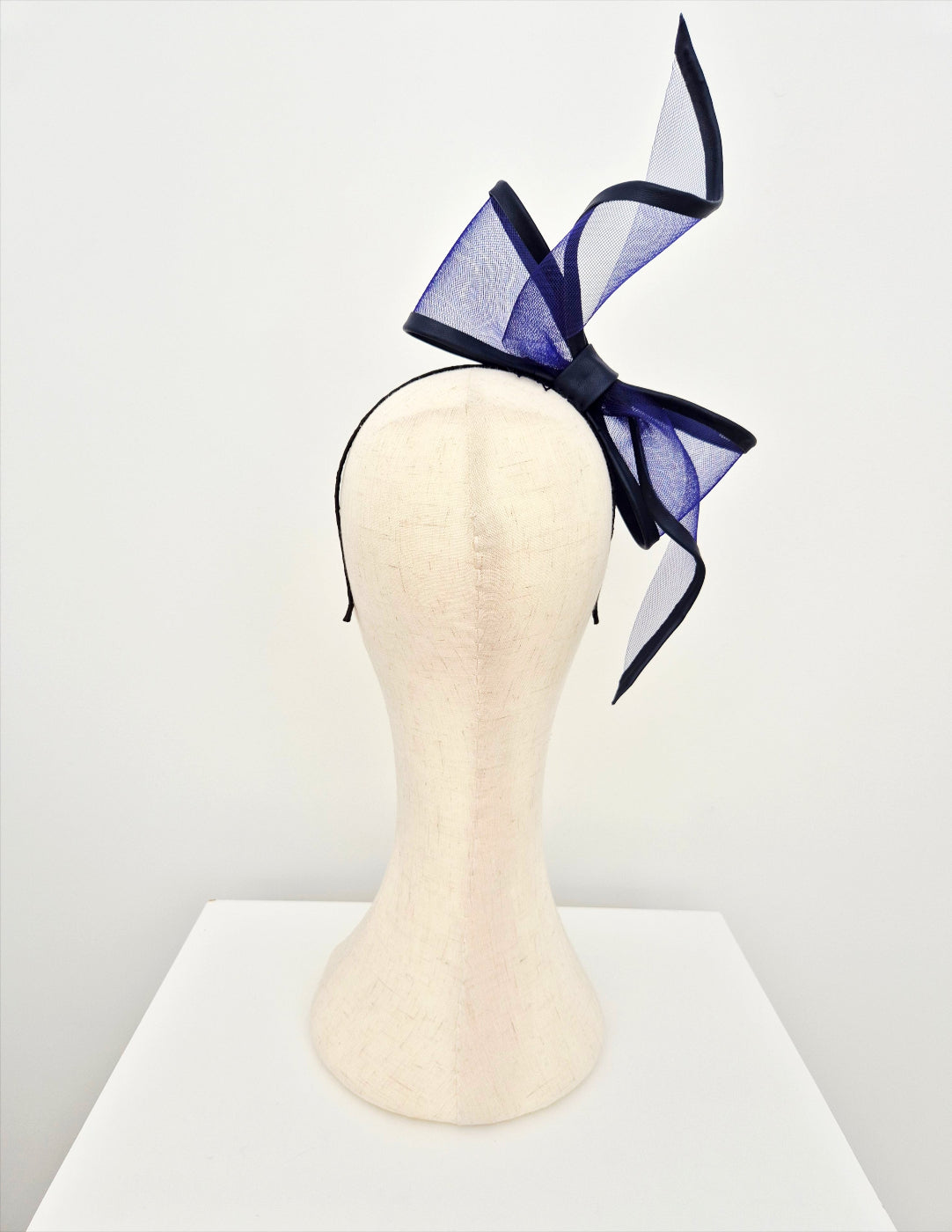 Navy blue bow headband on a mannequin head against a white background