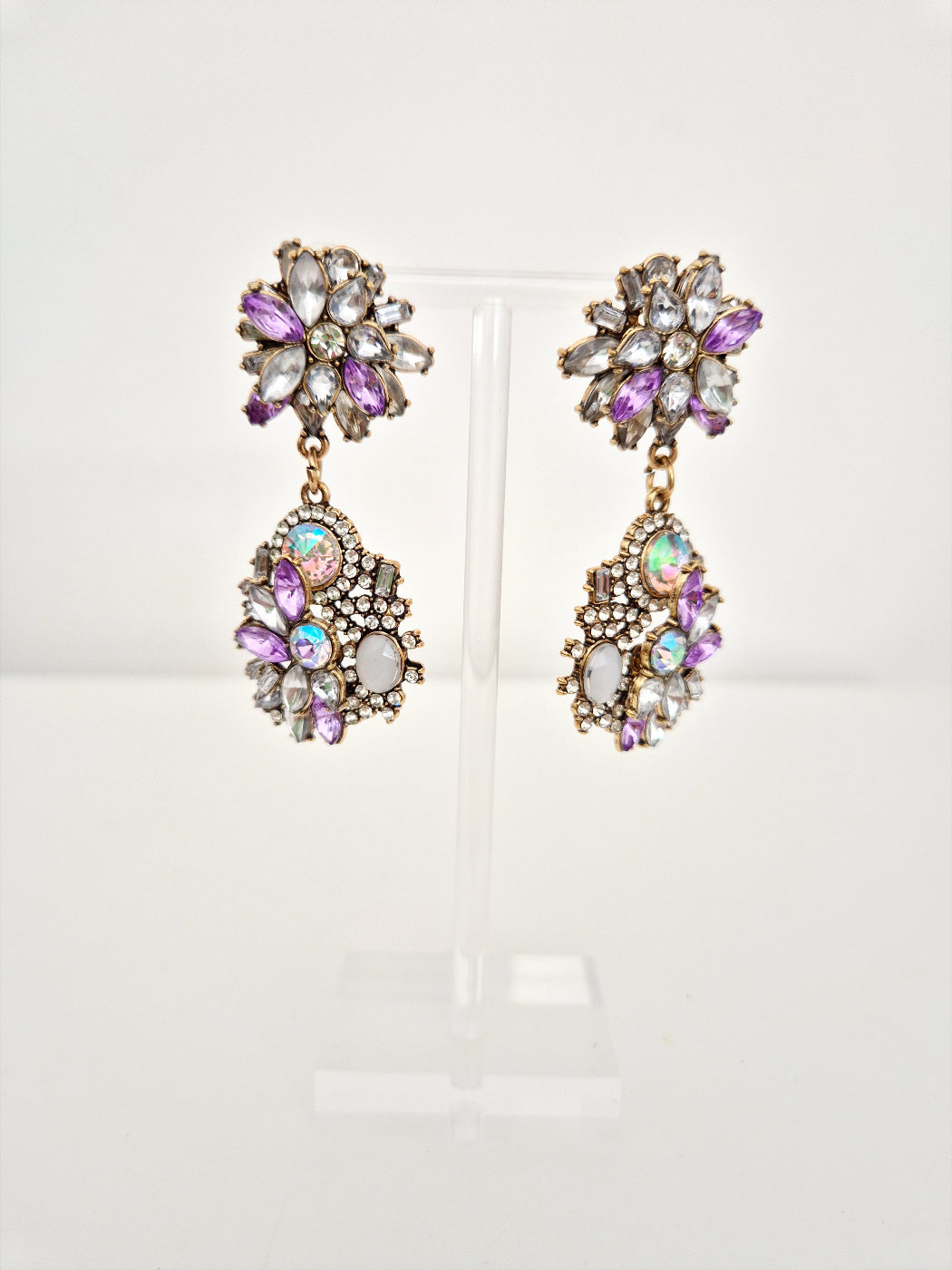 Pair of ornate earrings with colorful gemstones on a white background