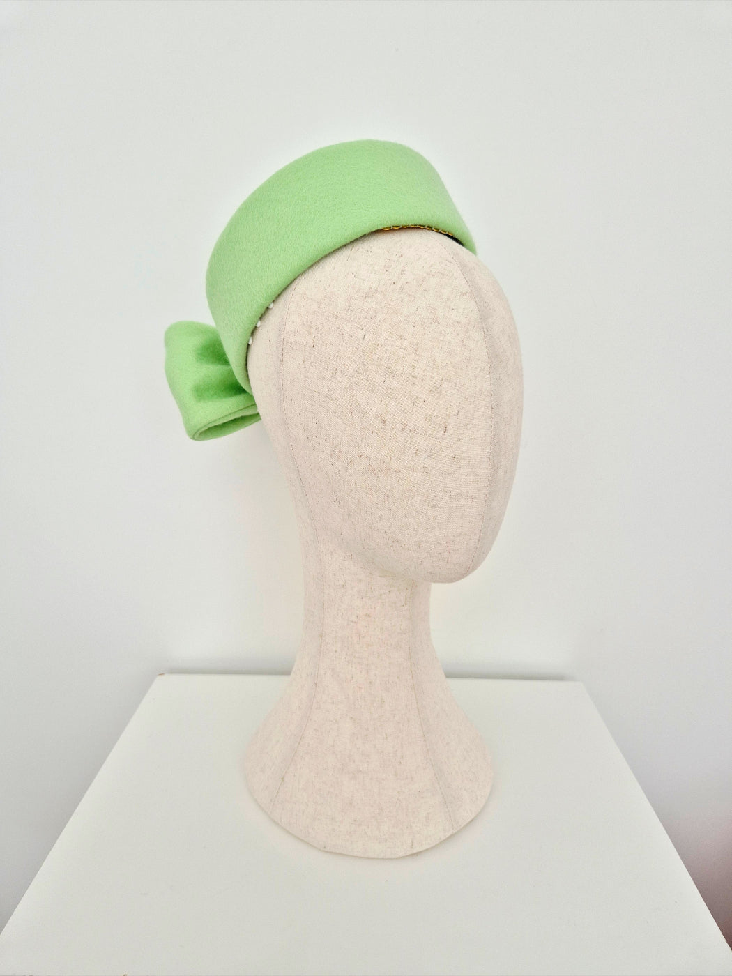 pale mint Green pillbox headpiece on a mannequin head against a white background view 2