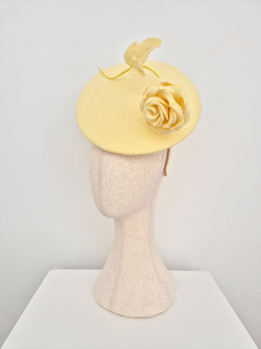 pale Yellow fascinator hat  with rose on a mannequin head against a white background side view