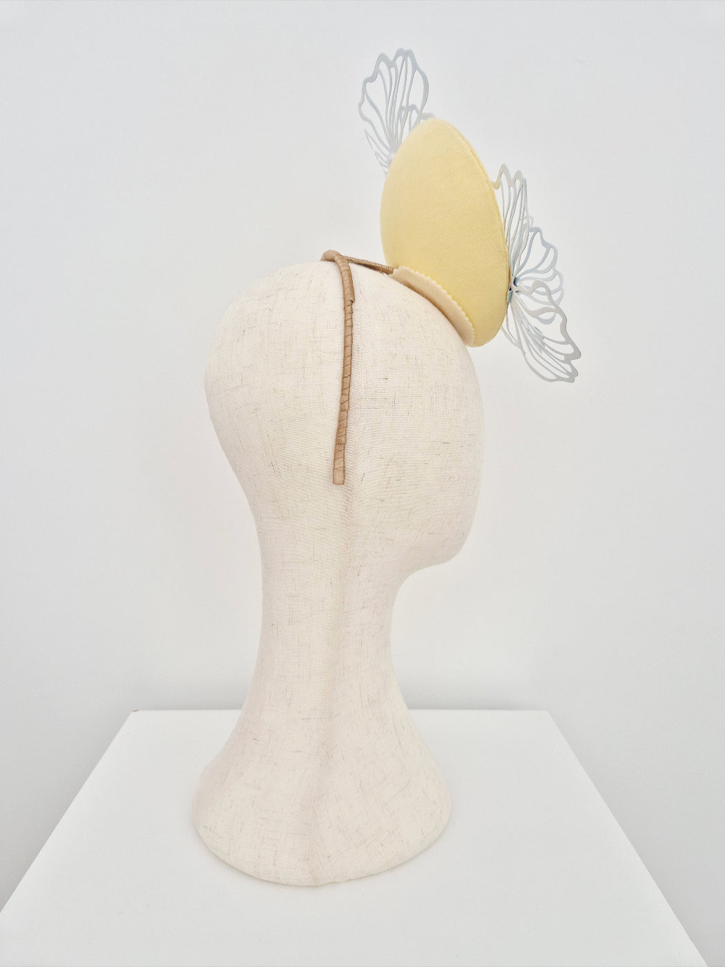 Mannequin head with a yellow headband and decorative elements on a white background side view