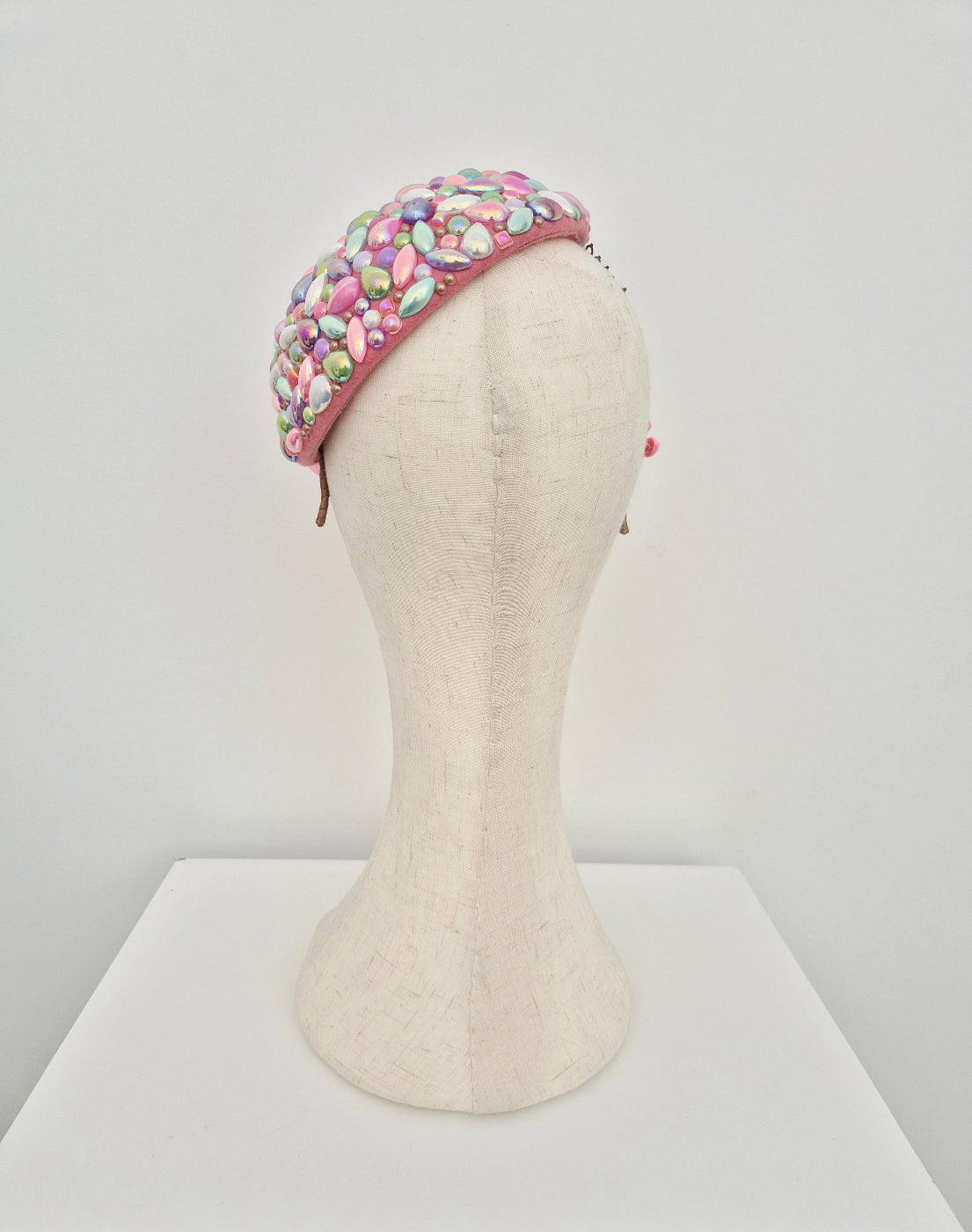 Colorful headpiece on a mannequin head against a white background back view