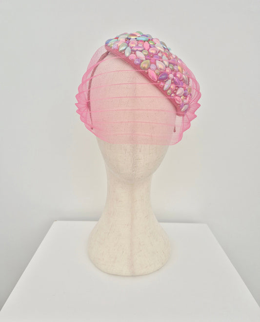 Pink headpiece with colorful beads on a mannequin head against a white background