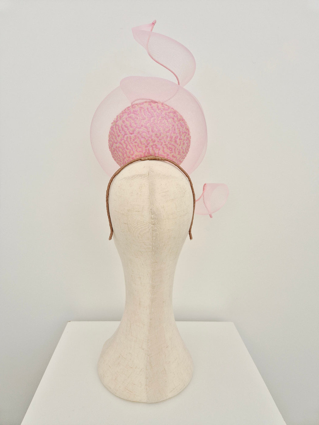 Light pink and cream  percher headpiece on a manniquin head on a white background back view