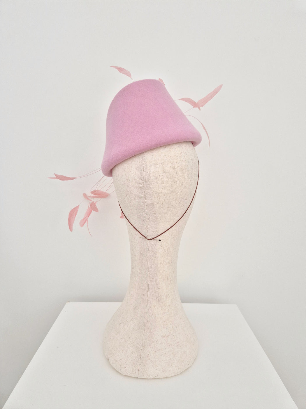 Pink felt hat on a mannequin head with a white background back view