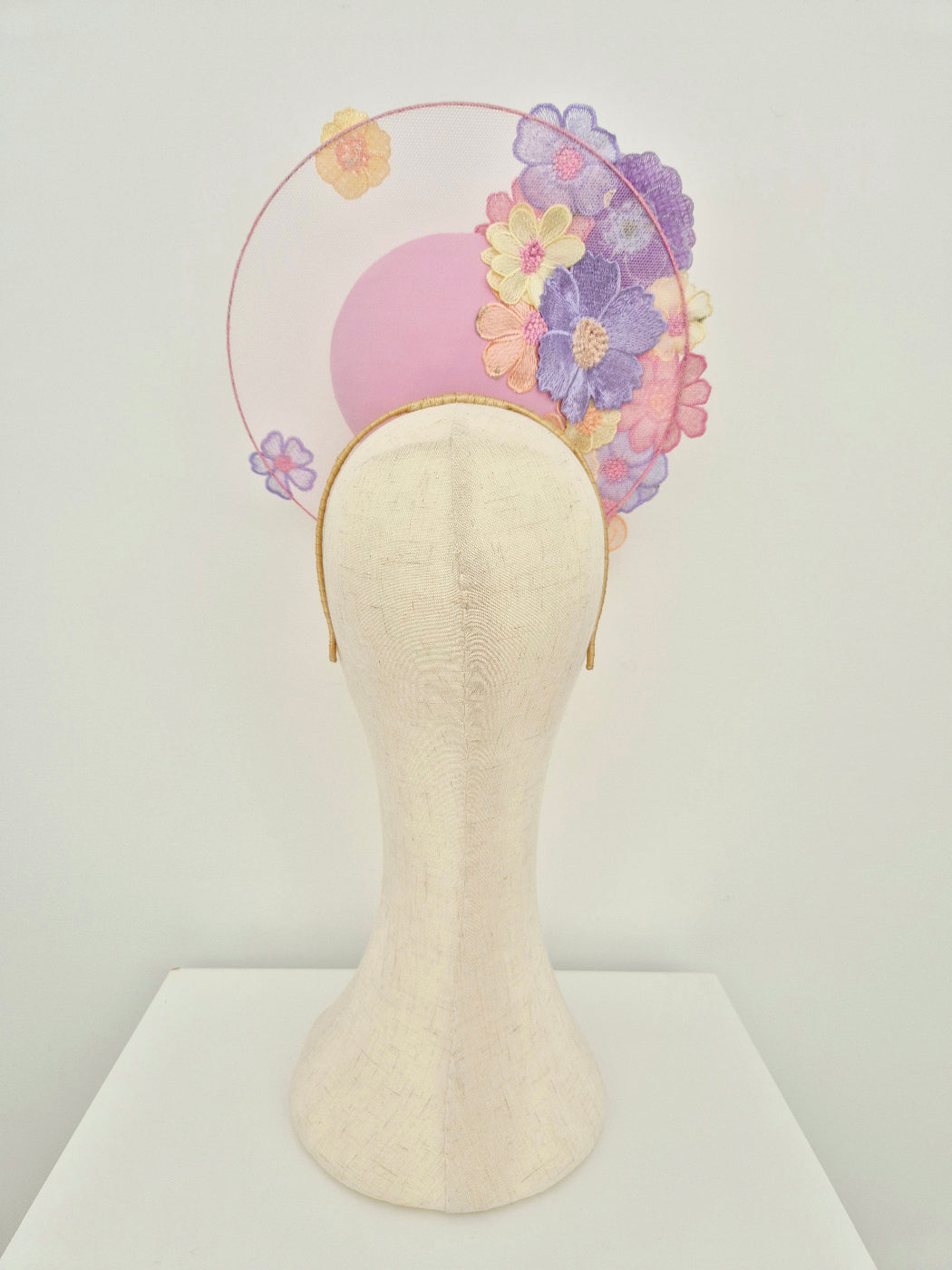 Pastel floral headband on a mannequin head against a white background back view