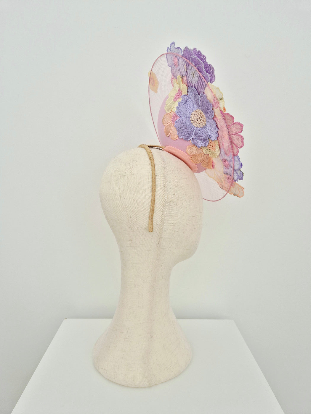 Pastel floral headband on a mannequin head against a white background side view