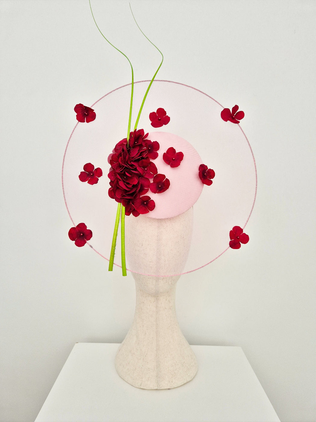 burgundy and pink floral headpiece on a mannequin head against a white background