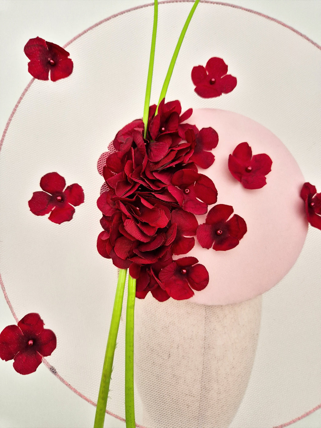 burgundy flowers on a pink headpiece on a white background close up
