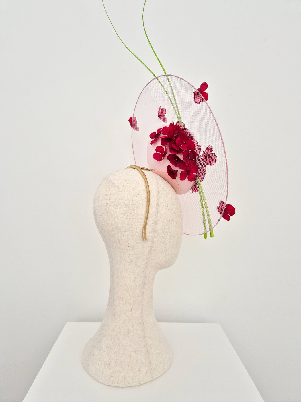 Mannequin head with a pink  decorative headpiece featuring burgundy flowers on a white background side view