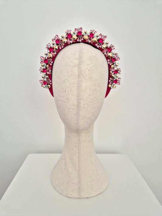 Decorative headband with pink and gold accents on a mannequin head against a white background