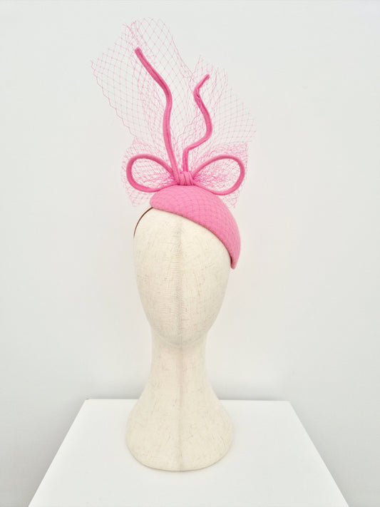 Pink headpiece with bow on a mannequin head against a white background