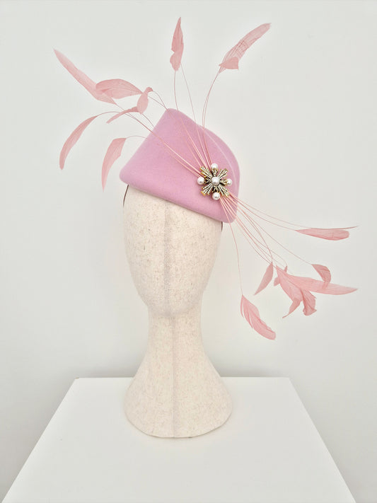 pink-felt-headpiece-with-feathers-on-a-manniquin head against a white background
