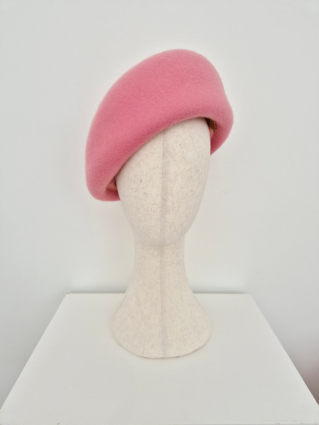 Pink oversized beret on a mannequin head against a white background