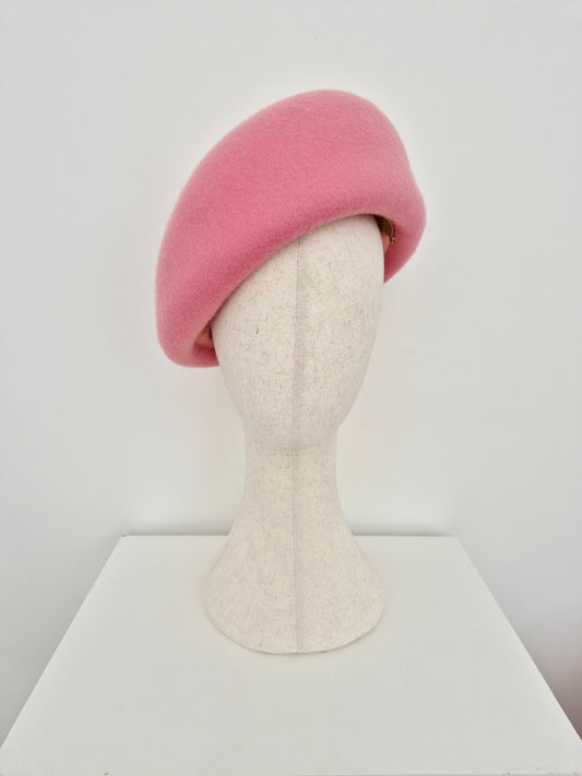 Pink oversized beret on a mannequin head against a white background