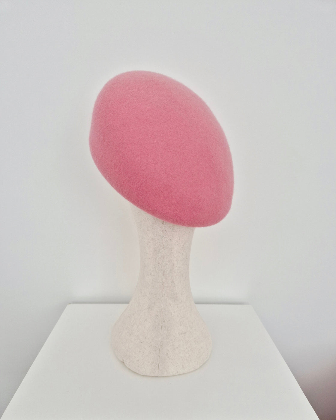 Pink oversized beret on a manniquin head against a white  background back view