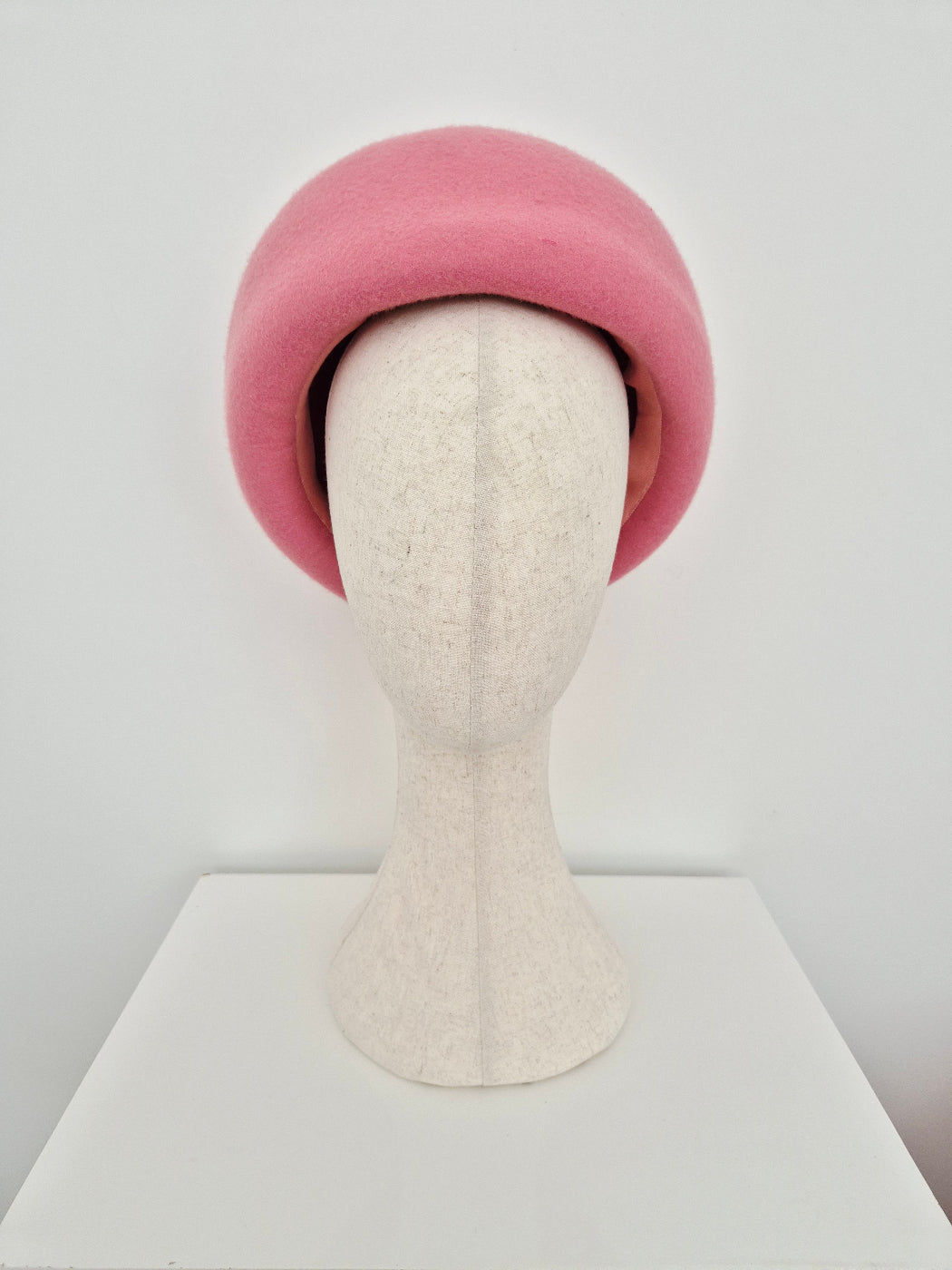 Pink oversized beret headpiece on a manniquin head  on a white background worn towards the back