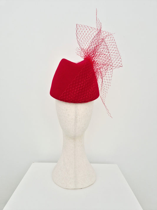 Red hat with a decorative net on a mannequin head against a white background