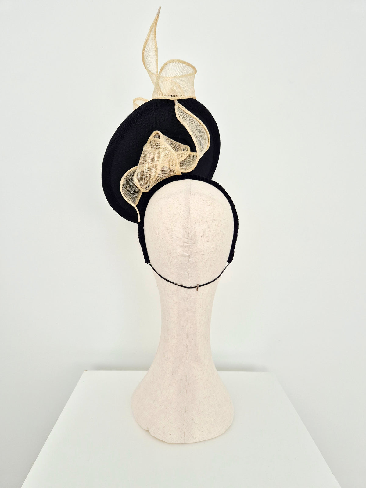 Miss Maya. Straw percher hat headpiece with a cream knotted swirl