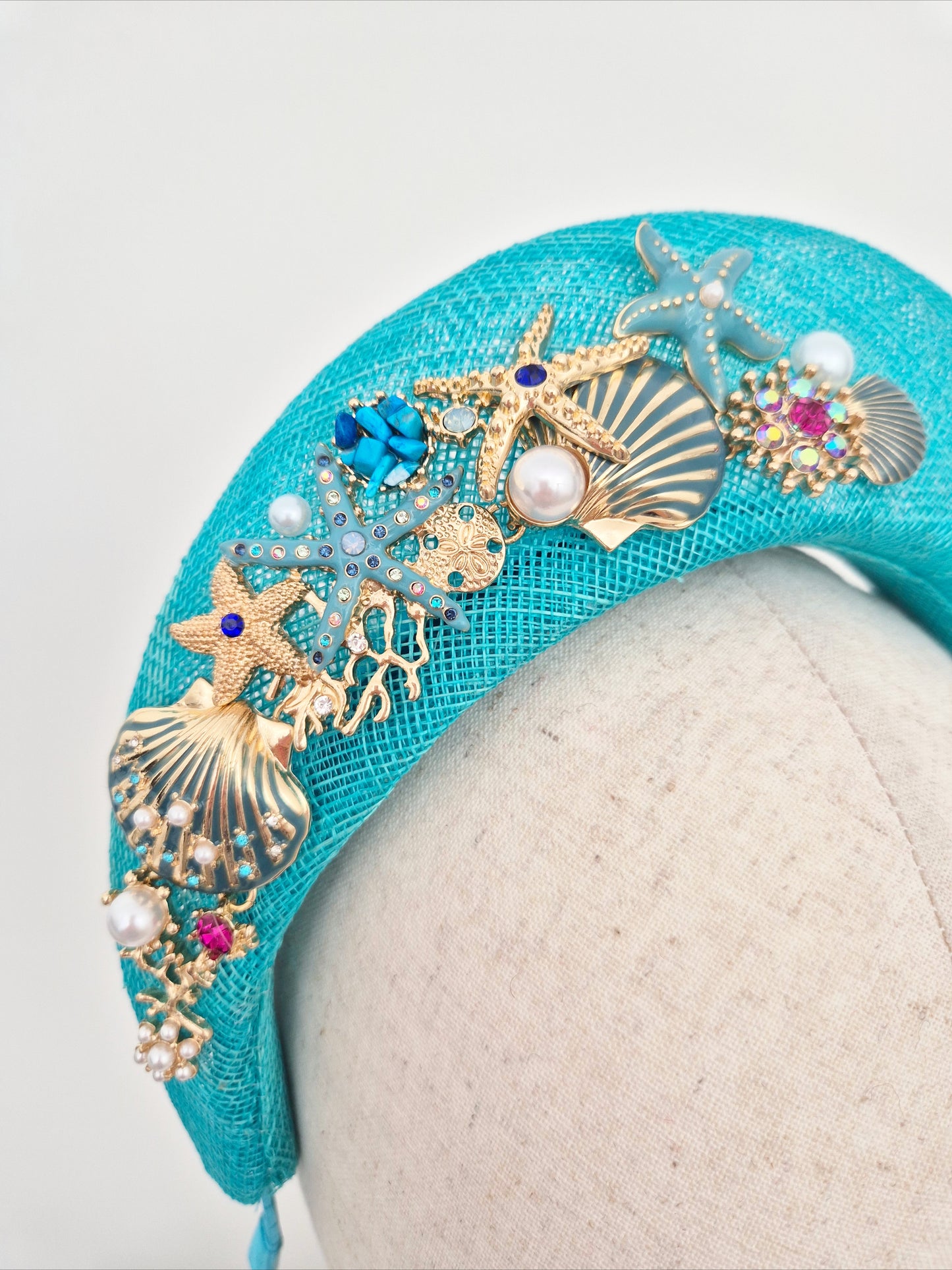 Miss Hanni. Turquoise blue sinamay halo headpiece with sea themed embellishment