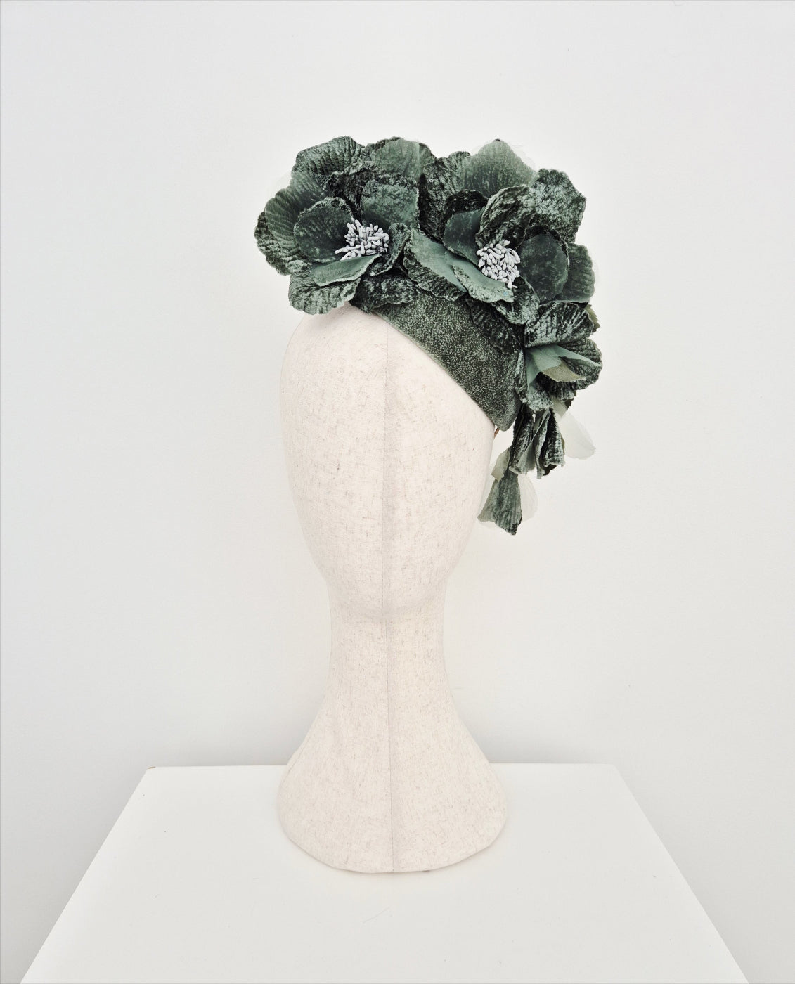 Green floral headpiece on a mannequin head against a white background