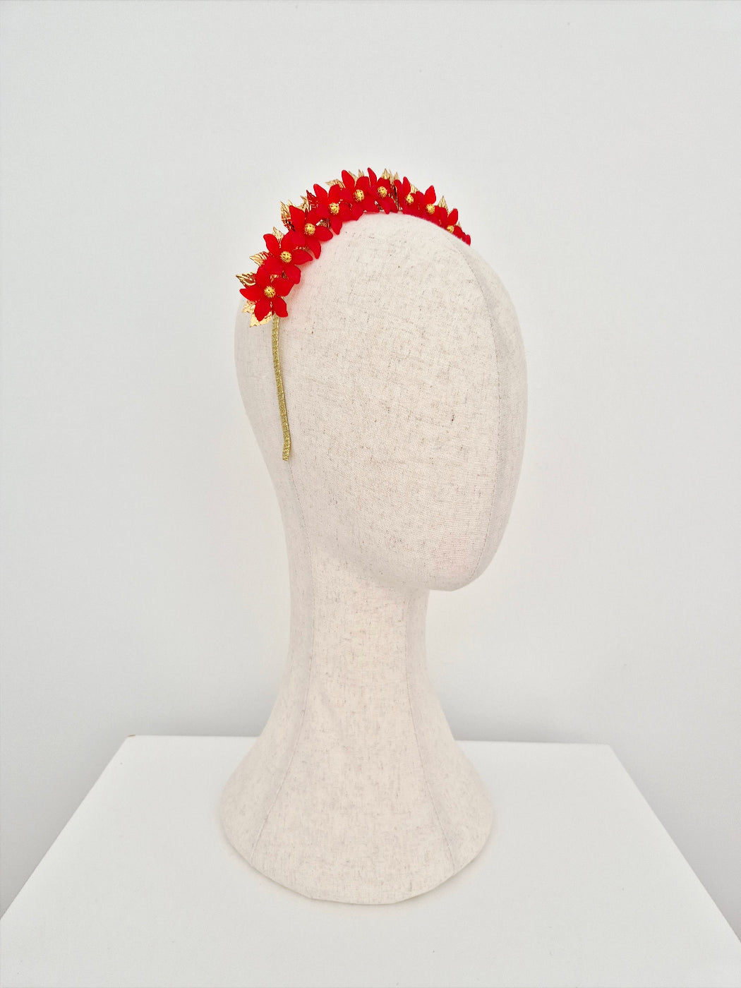 Red floral headband on a mannequin head against a white background side view