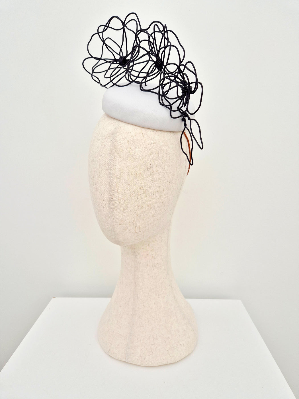 side view white button headpiece with black floral wirework