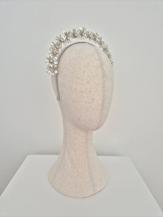 Silver headband with floral design on a mannequin head against a plain background side view
