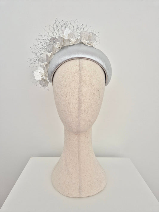 Silver headpiece with floral details on a mannequin head against a white background