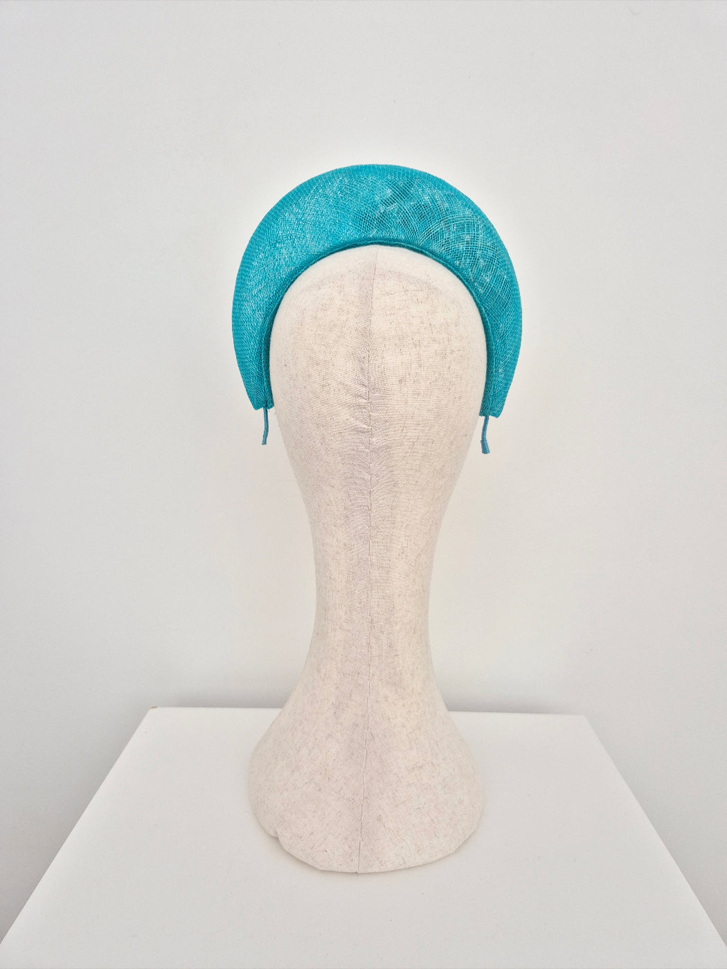 Blue headband on a mannequin head against a white background back view